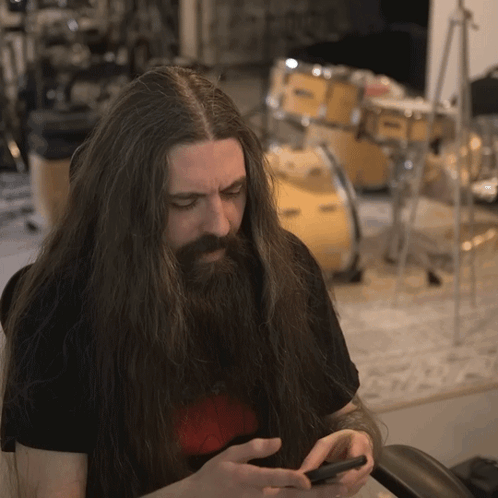 Man With Long Hair And Beard Looking At Phone GIF