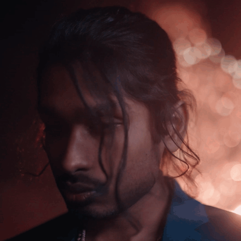 A Man With Long Hair And A Beard Looks Down At Something GIF