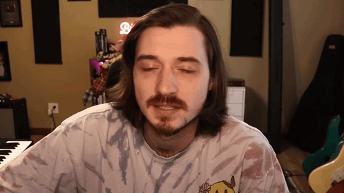 a man with long hair and a beard wearing a tie dye shirt with a smiley face on it