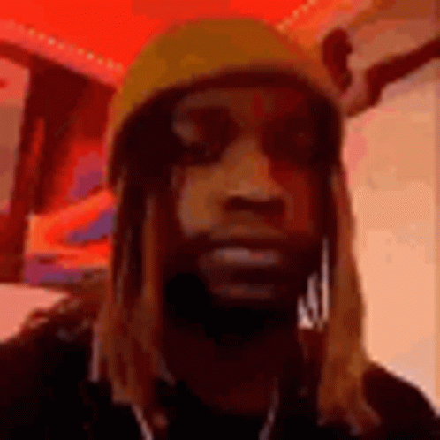 A Man With Long Hair And A Beard Wearing A Yellow Hat And Earrings . GIF
