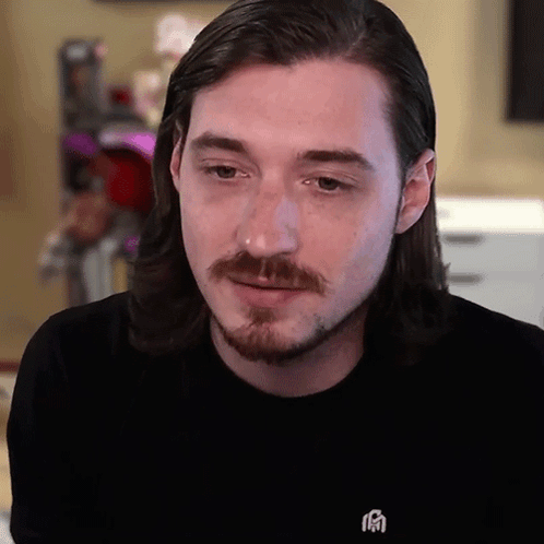 A Man With Long Hair And A Beard Wears A Black Shirt With A Chinese Symbol On The Front GIF
