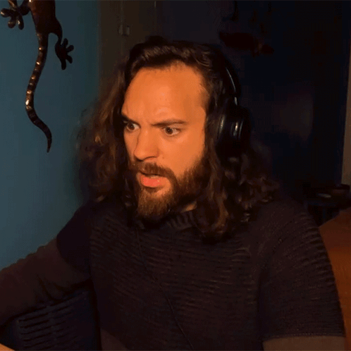 A Man With Long Hair And A Beard Wears Headphones GIF