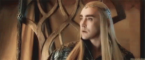 a man with long hair and a crown on his head is sitting in a chair .
