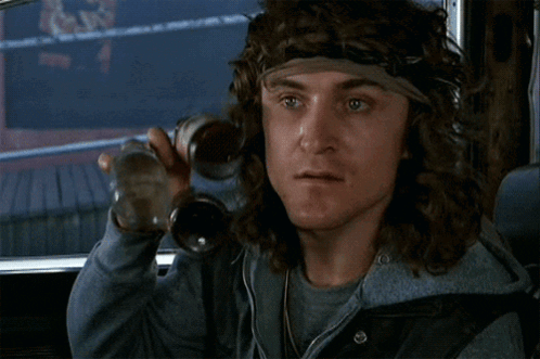 a man with long hair and a headband is holding a bottle