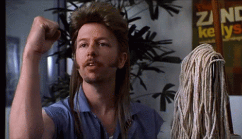 A Man With Long Hair And A Mop Has His Fist Up GIF