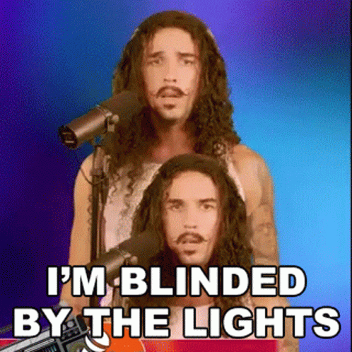 A Man With Long Hair And A Mustache Is Singing Into A Microphone And Says I 'M Blinded By The Lights GIF