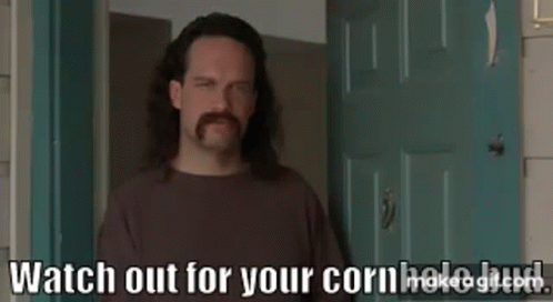 A Man With Long Hair And A Mustache Is Standing In Front Of A Door And Talking . GIF