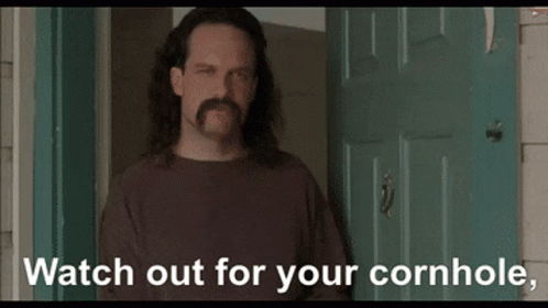A Man With Long Hair And A Mustache Is Standing In Front Of A Door With The Words " Watch Out For Your Cornhole " Below GIF