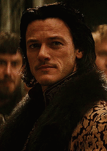 A Man With Long Hair And A Mustache Is Wearing A Fur Collar GIF