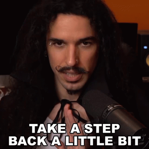 A Man With Long Hair And A Mustache Stands In Front Of A Microphone With The Words Take A Step Back A Little Bit Below H GIF