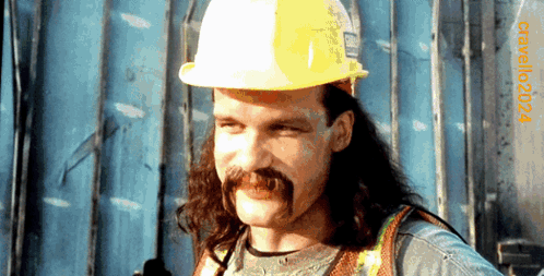 A Man With Long Hair And A Mustache Wearing A Hard Hat With The Year 2004 On The Bottom Right GIF
