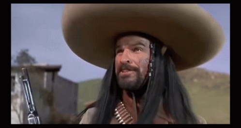 A Man With Long Hair And A Sombrero Is Holding A Gun In His Hand . GIF