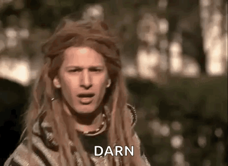 a man with long hair and dreadlocks is wearing a blanket and making a face .