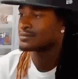 A Man With Long Hair And Dreadlocks Wearing A Hat And Earrings . GIF