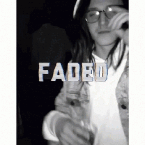 A Man With Long Hair And Glasses Is Holding A Microphone And The Word Faded Is On The Bottom GIF