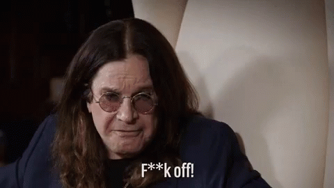 A Man With Long Hair And Glasses Is Sitting On A Chair And Making A Funny Face . GIF