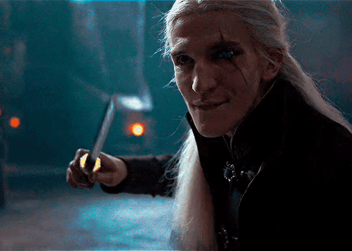 A Man With Long Hair Is Holding A Knife In His Hand GIF
