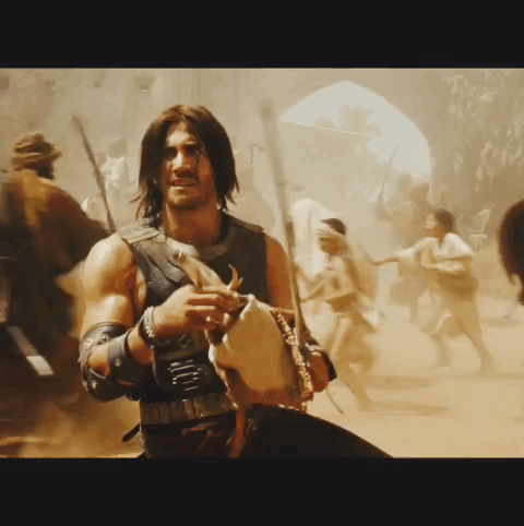 A Man With Long Hair Is Holding A Sword In A Crowd GIF