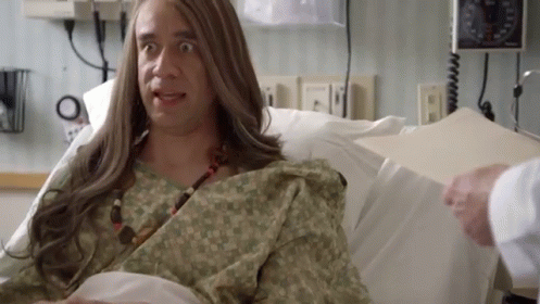 A Man With Long Hair Is Laying In A Hospital Bed With A Doctor . GIF