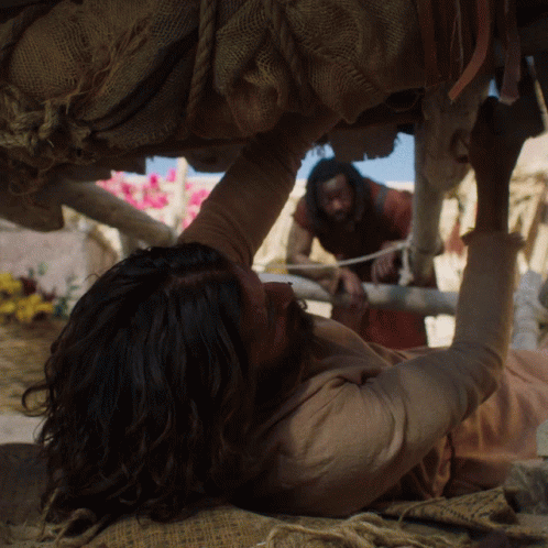 A Man With Long Hair Is Laying On The Ground With His Arm Up GIF