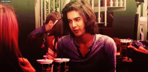 A Man With Long Hair Is Looking At A Woman While Sitting At A Table With Drinks In Front Of Him .. GIF