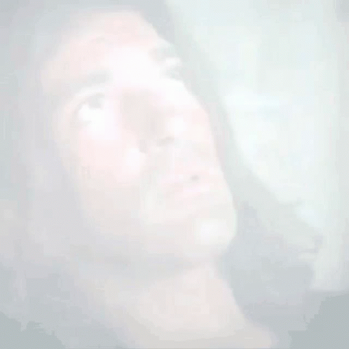 A Man With Long Hair Is Looking Up At Something . GIF