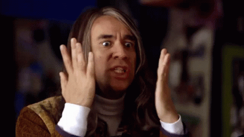 A Man With Long Hair Is Making A Funny Face With His Hands GIF