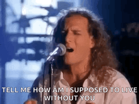 A Man With Long Hair Is Singing Into A Microphone And Says `` Tell Me How Am I Supposed To Live Without You '' GIF