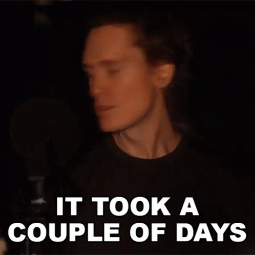 A Man With Long Hair Is Singing Into A Microphone And The Words `` It Took A Couple Of Days '' Are Written Above Him . GIF