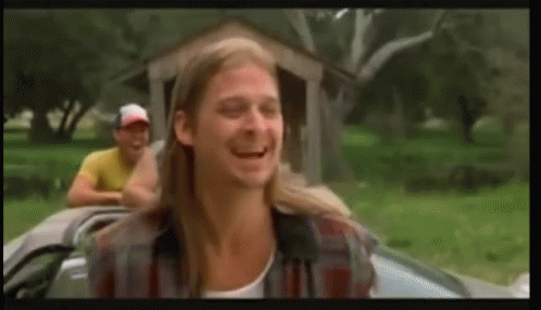 A Man With Long Hair Is Sitting In A Car With Another Man Behind Him . GIF