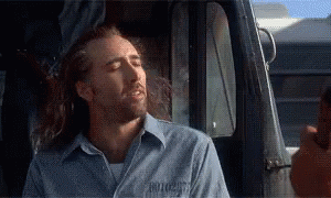 A Man With Long Hair Is Sitting In The Driver 'S Seat Of A Truck With His Eyes Closed . GIF