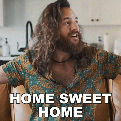 A Man With Long Hair Is Sitting On A Couch And Says Home Sweet Home GIF