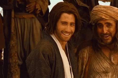 A Man With Long Hair Is Smiling In Front Of A Group Of People GIF