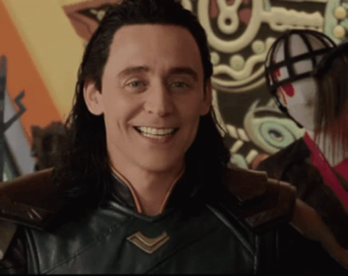 A Man With Long Hair Is Smiling In Front Of A Shield With The Letter O On It GIF