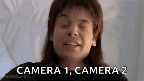 A Man With Long Hair Is Smiling With His Eyes Closed And The Words `` Camera 1 , Camera 2 '' Written Next To Him . GIF
