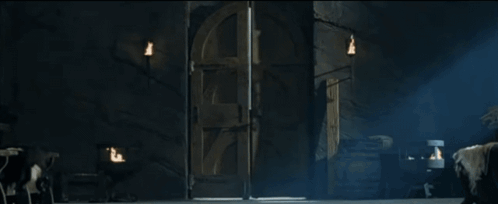 A Man With Long Hair Is Standing In A Dark Room Holding A Door Open GIF