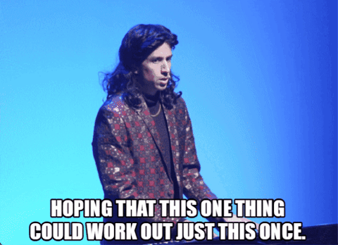 Long-Haired Man Standing In Front Of Blue Background Hoping For Something GIF