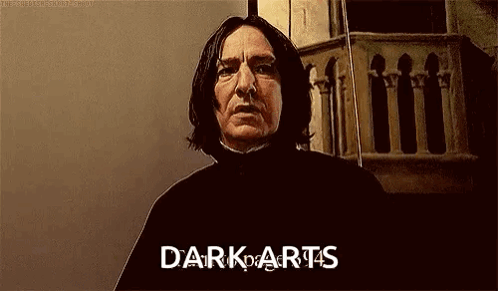 A Man With Long Hair Is Standing In Front Of A Building With The Words `` Dark Arts '' Written On His Face . GIF