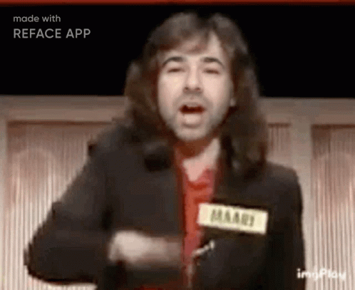 A Man With Long Hair Is Standing In Front Of A Microphone And Talking . GIF