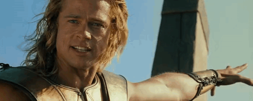 A Man With Long Hair Is Standing In Front Of A Tower With His Arm Outstretched . GIF