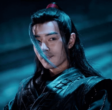 A Man With Long Hair Is Wearing A Black Jacket And Has A Red Ponytail . GIF