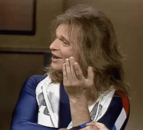 A Man With Long Hair Is Wearing A Blue White And Red Shirt GIF
