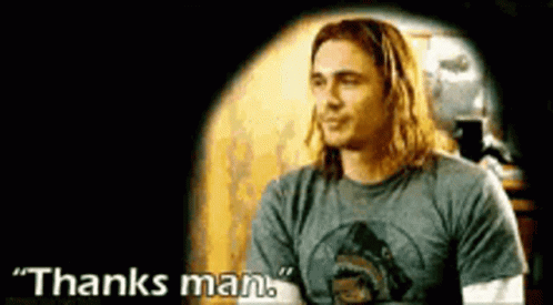 A Man With Long Hair Is Wearing A Gray Shirt And Says Thanks Man . GIF