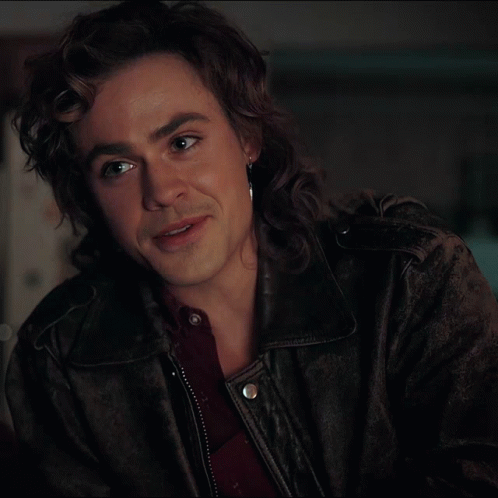 A Man With Long Hair Is Wearing A Leather Jacket And Earrings GIF