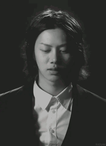 A Man With Long Hair Is Wearing A Suit And A White Shirt With Radsam Written On The Bottom GIF