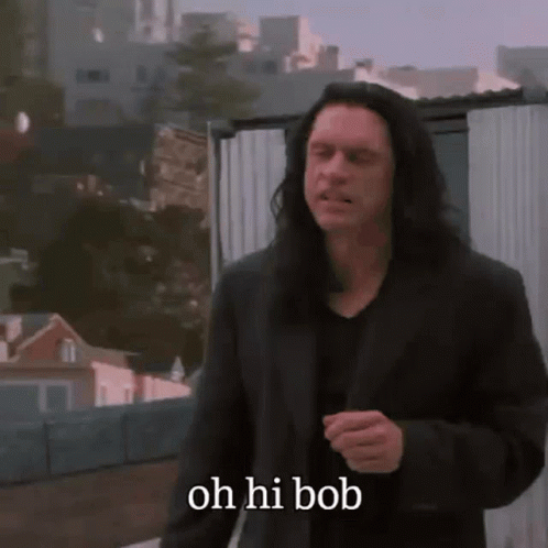 A Man With Long Hair Says Oh Hi Bob While Walking Down A Street GIF