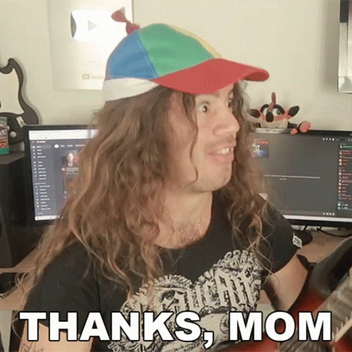 A Man With Long Hair Wearing A Hat And A Shirt That Says " Thanks Mom " GIF