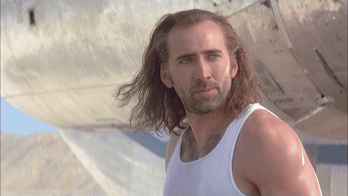 A Man With Long Hair Wearing A White Tank Top GIF