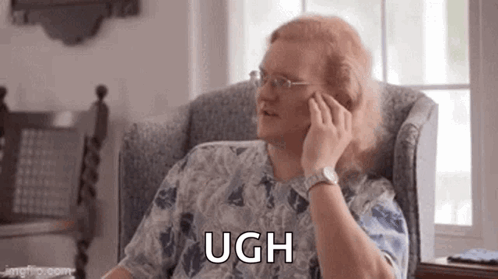 A Man With Long Red Hair Is Sitting In A Chair Talking On A Cell Phone . GIF