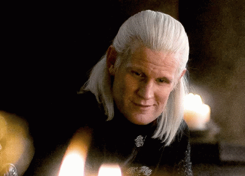 a man with long white hair is sitting in front of a candle